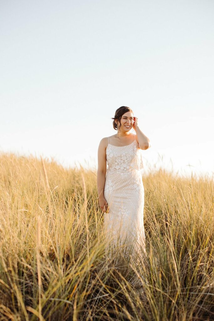 bride standing in the grass at sunset