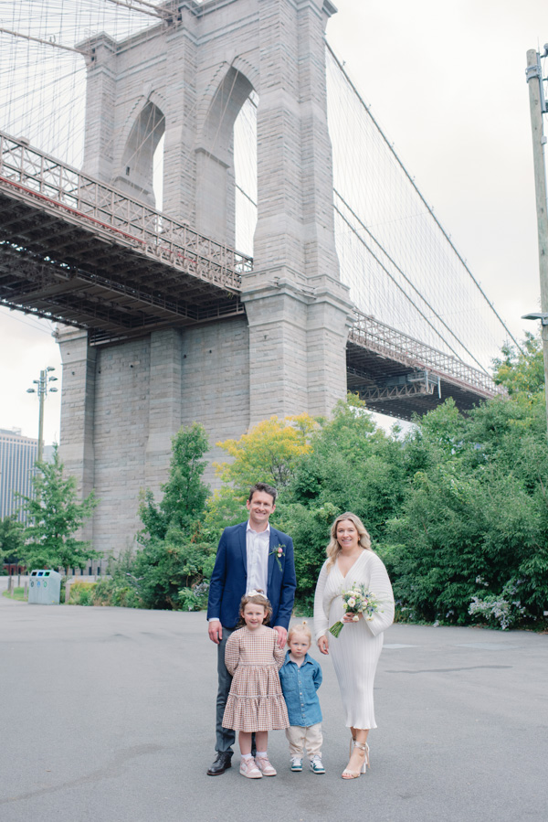 married couple with kid a front of brooklyn bridge in nyc